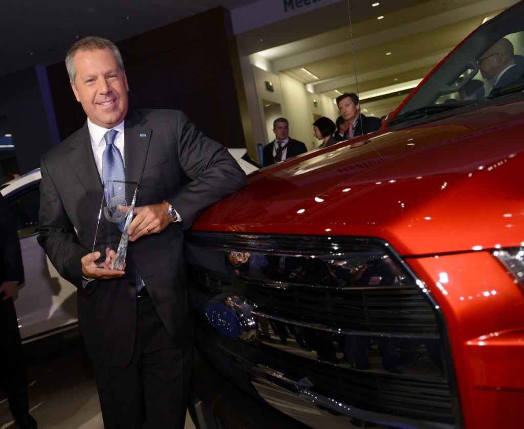 Joe Hinrichs, Ford president of The Americas, holds the TOTY trophy while leaning on the 2015 F-150